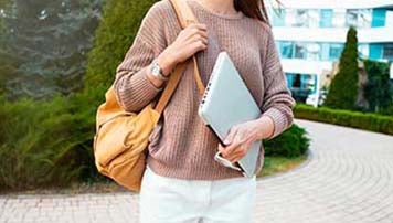 woman wearing bag and holding laptop