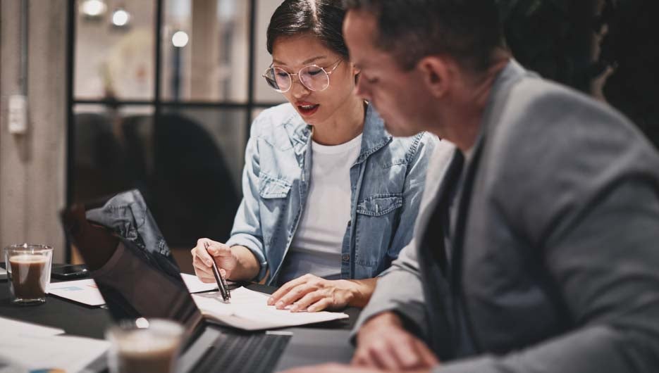 Two businesspeople sitting at a table and going over paperwork