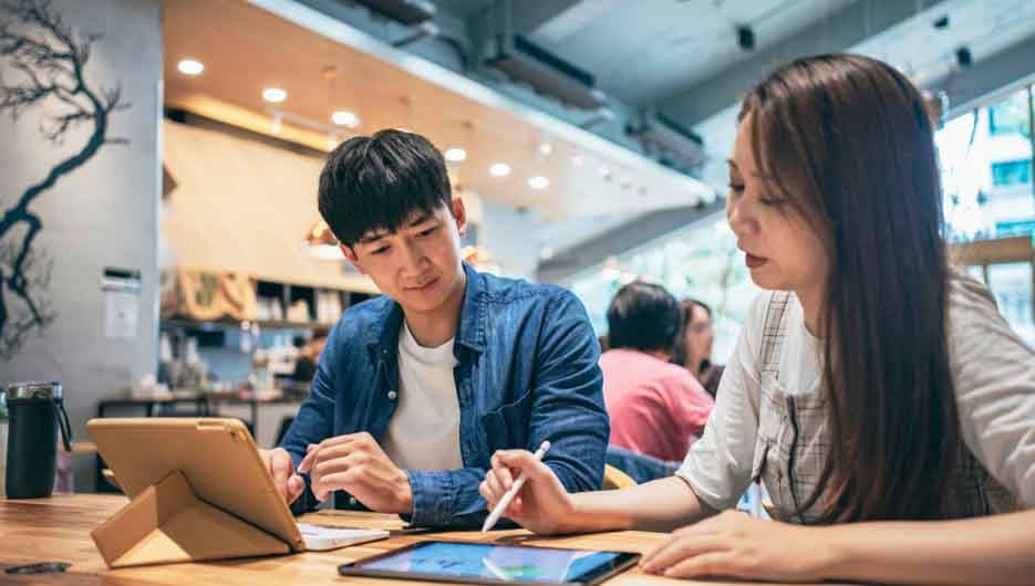 In a cozy cafe setting, two young entrepreneurs engage in a lively discussion about their work.