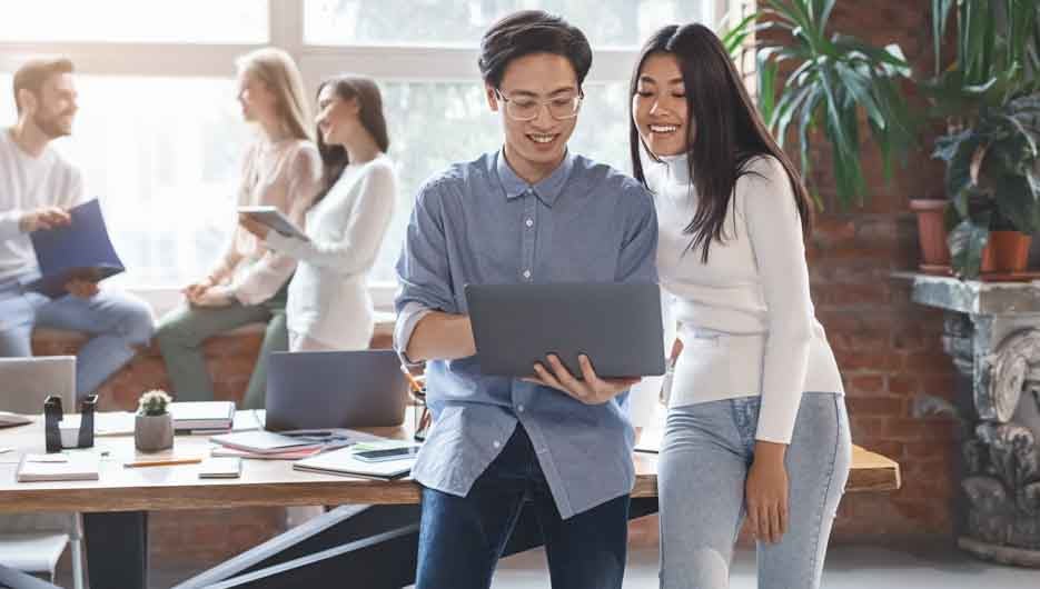 Excited asian guy sharing business ideas with young woman cowork