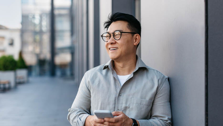 Confident korean middle aged businessman holding smartphone and 