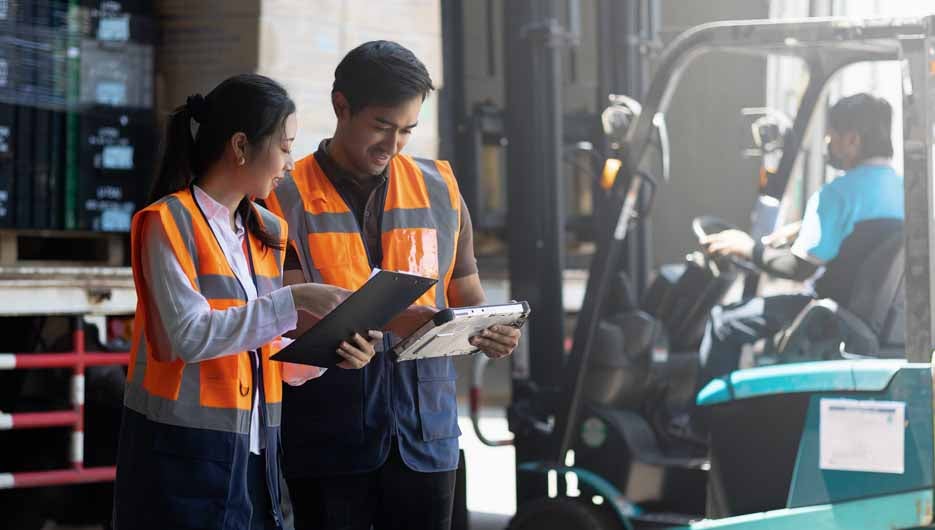 Warehouse worker and manager checks stock and inventory with digital tablet computer in the retail warehouse full of shelves with goods. Working in logistics, Distribution center.